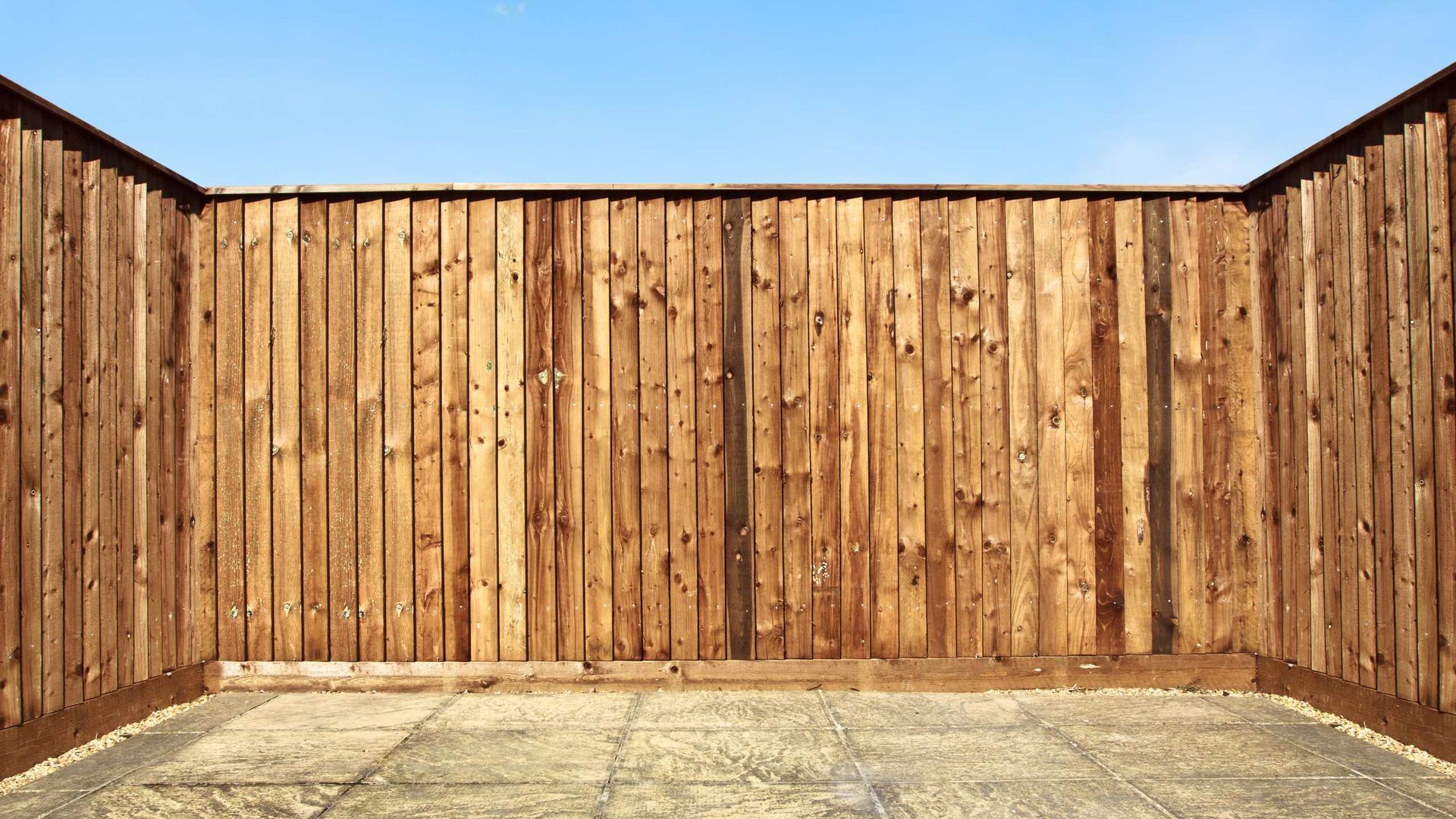 An empty room with a wooden fence and a concrete floor.