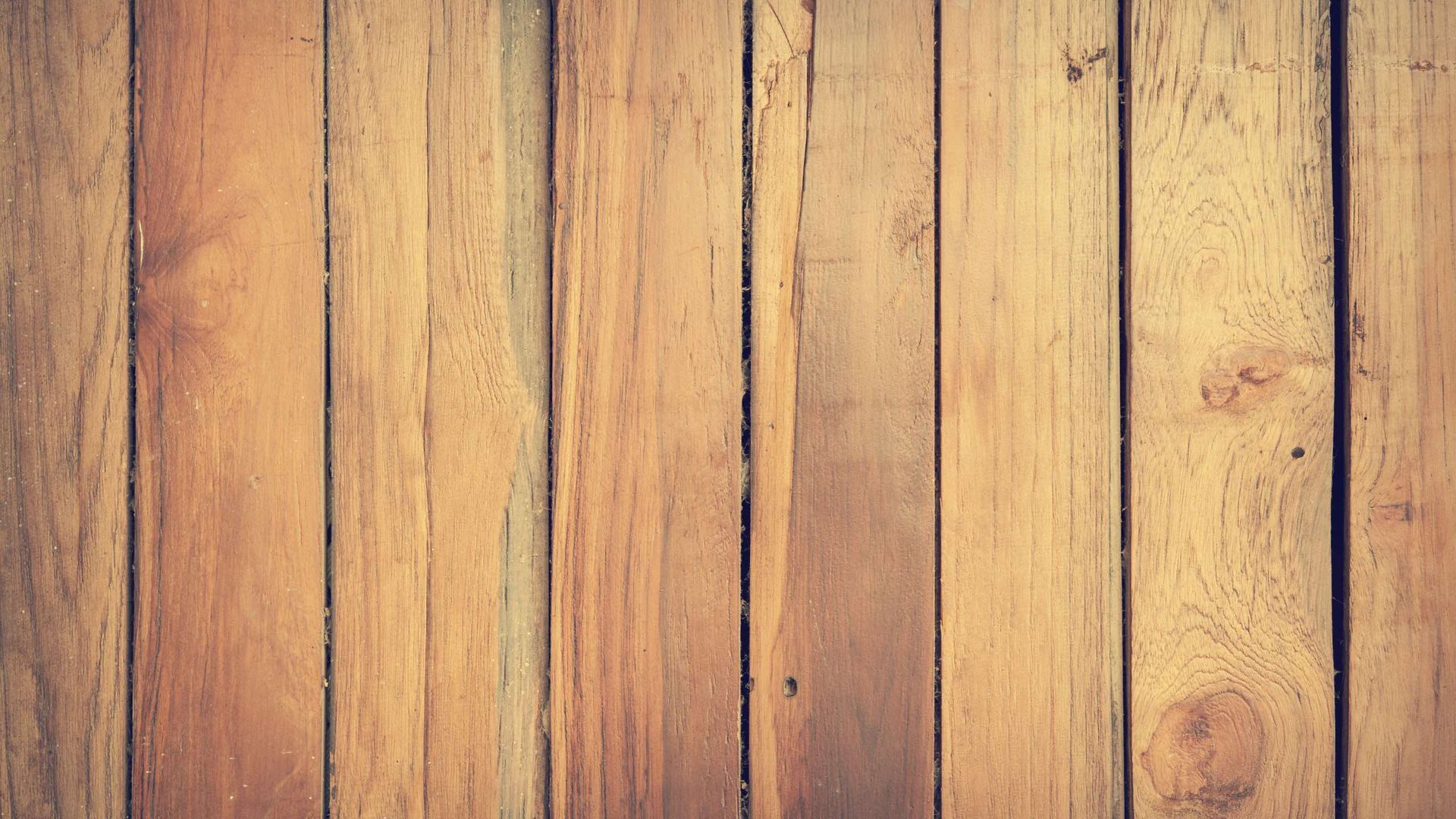 A close up of a wooden floor with a wooden fence in the background.