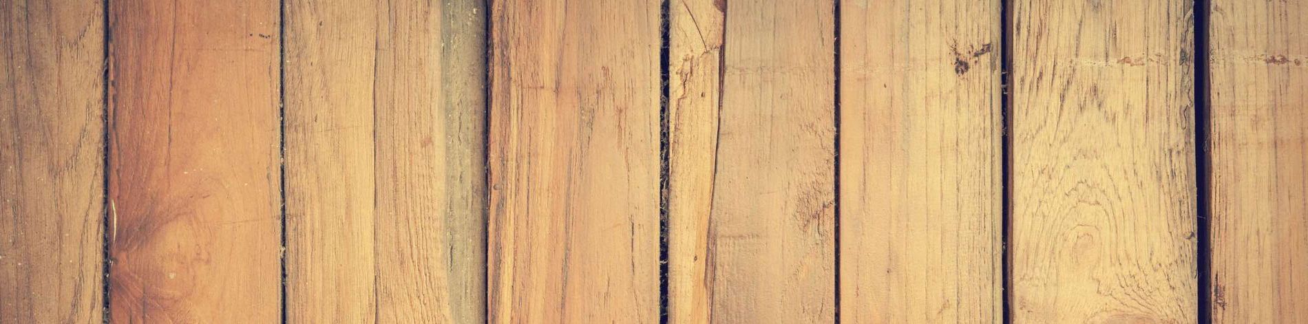 A close up of a wooden floor with a wooden fence in the background.