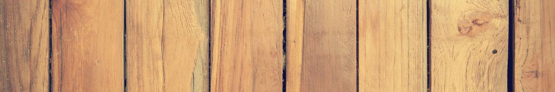 A close up of a wooden floor with a wooden fence in the background.