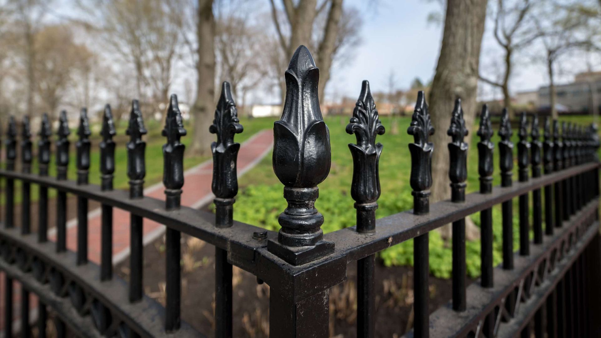 A close up of a black wrought iron fence in a park.