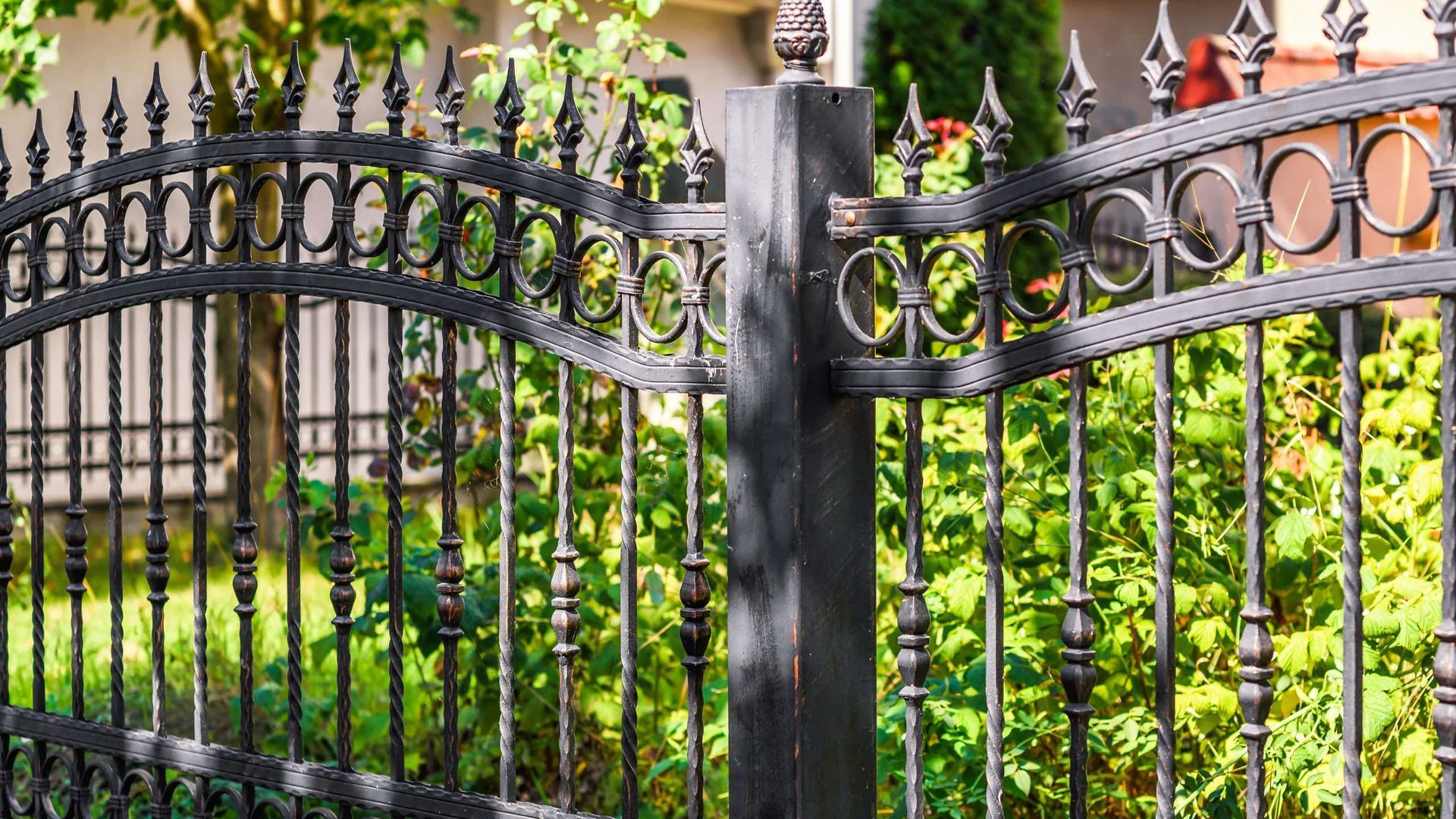 A close up of a wrought iron fence in front of a house.
