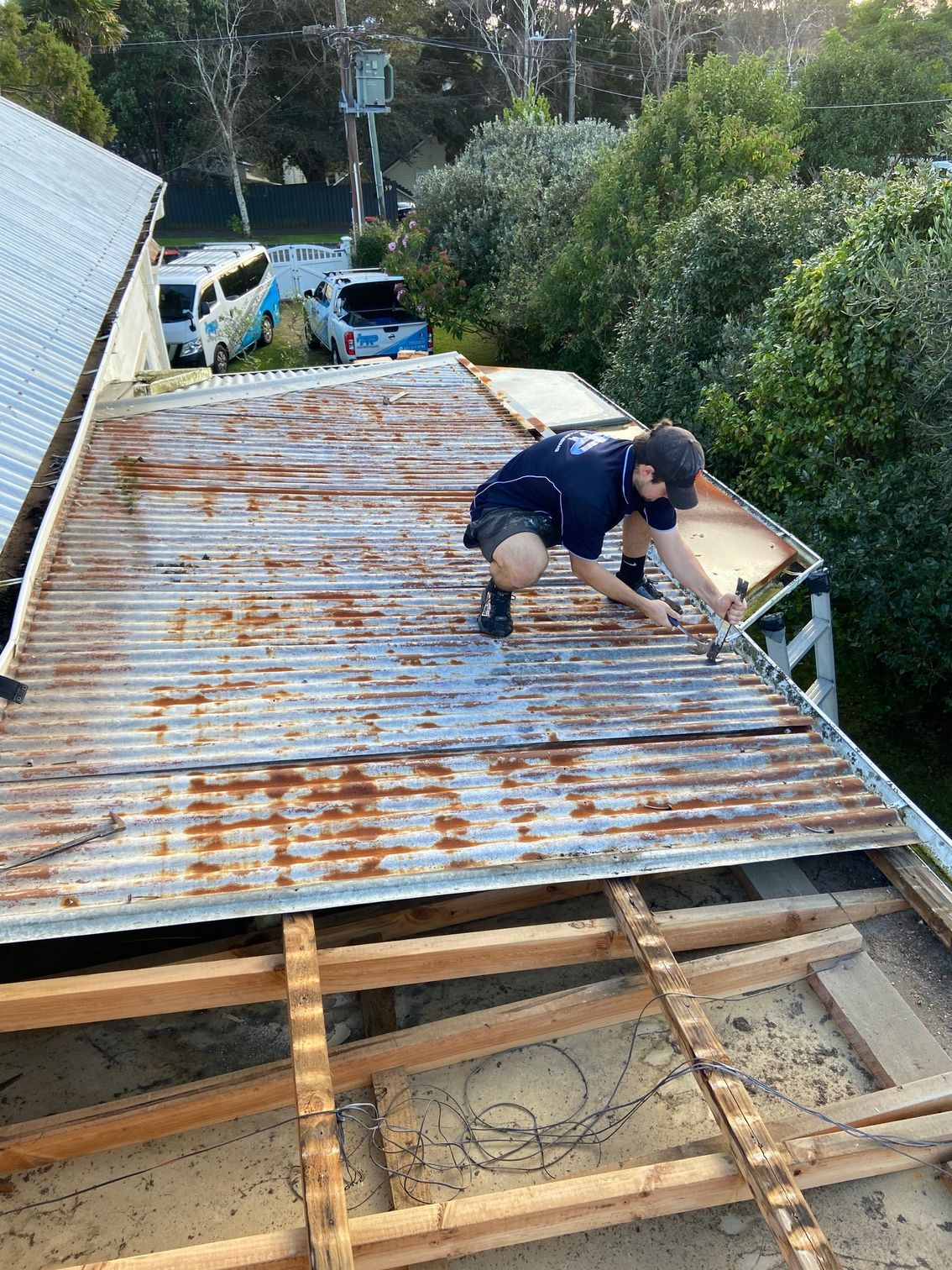 Man removing rusty corrugated metal roof panels. Exterior shot.