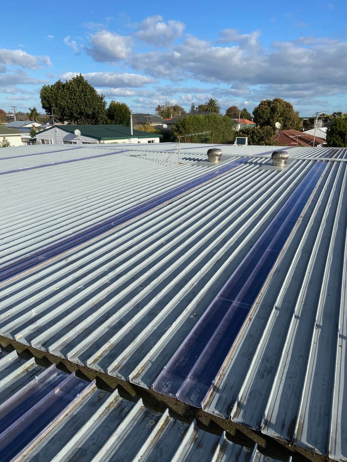 Corrugated metal roof with transparent panels, blue sky.