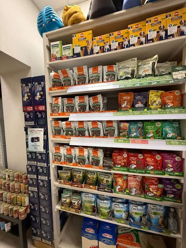 In un negozio, uno scaffale è rifornito con diverse confezioni colorate di cibo e snack per animali domestici.