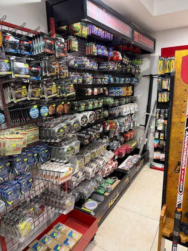 In un negozio al dettaglio, gli scaffali sono pieni di attrezzatura da pesca e esche confezionate di vario tipo.