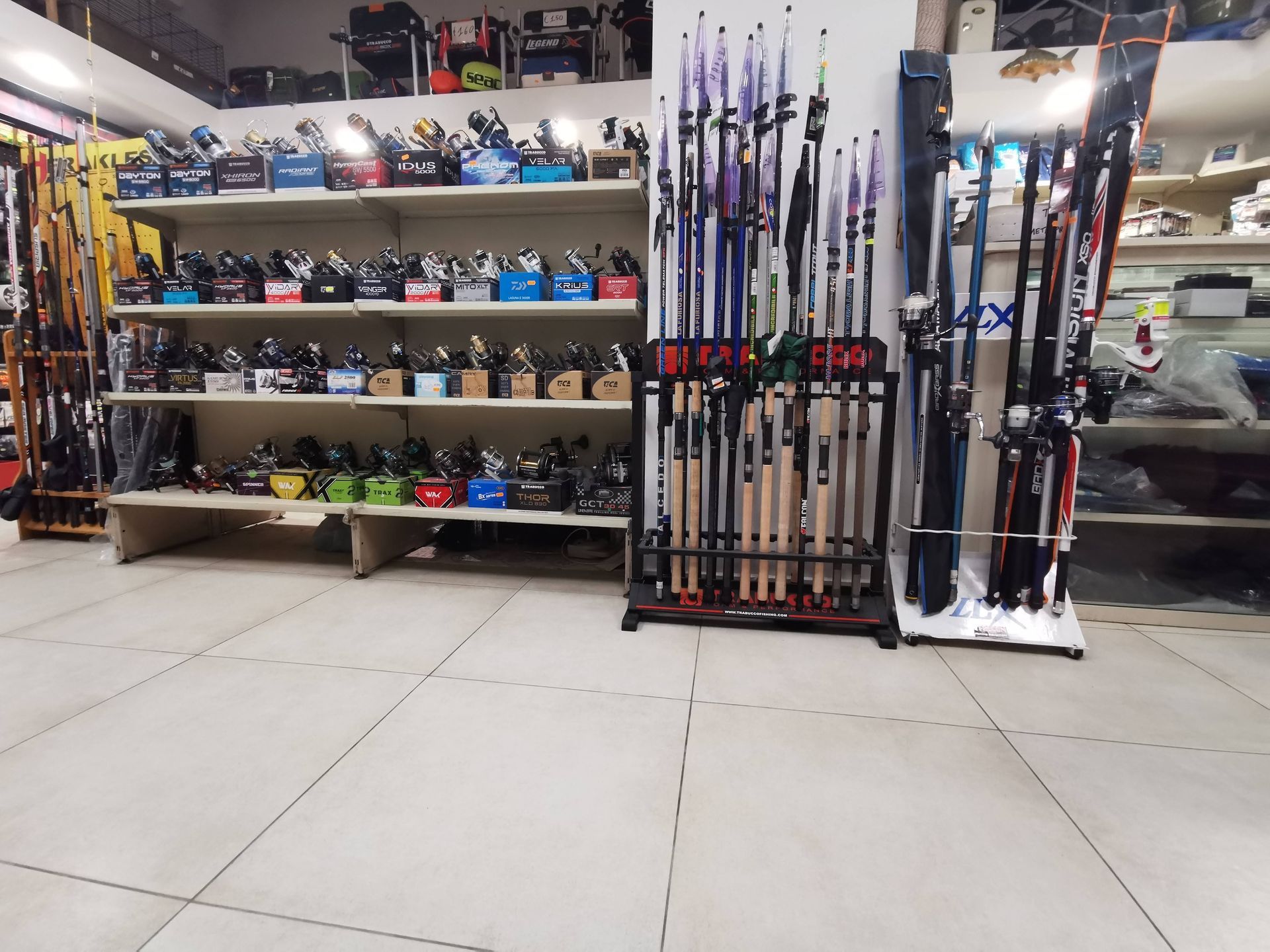 Un negozio di articoli sportivi con scaffali pieni di mazze da golf e rastrelliere di canne da pesca su un pavimento piastrellato.