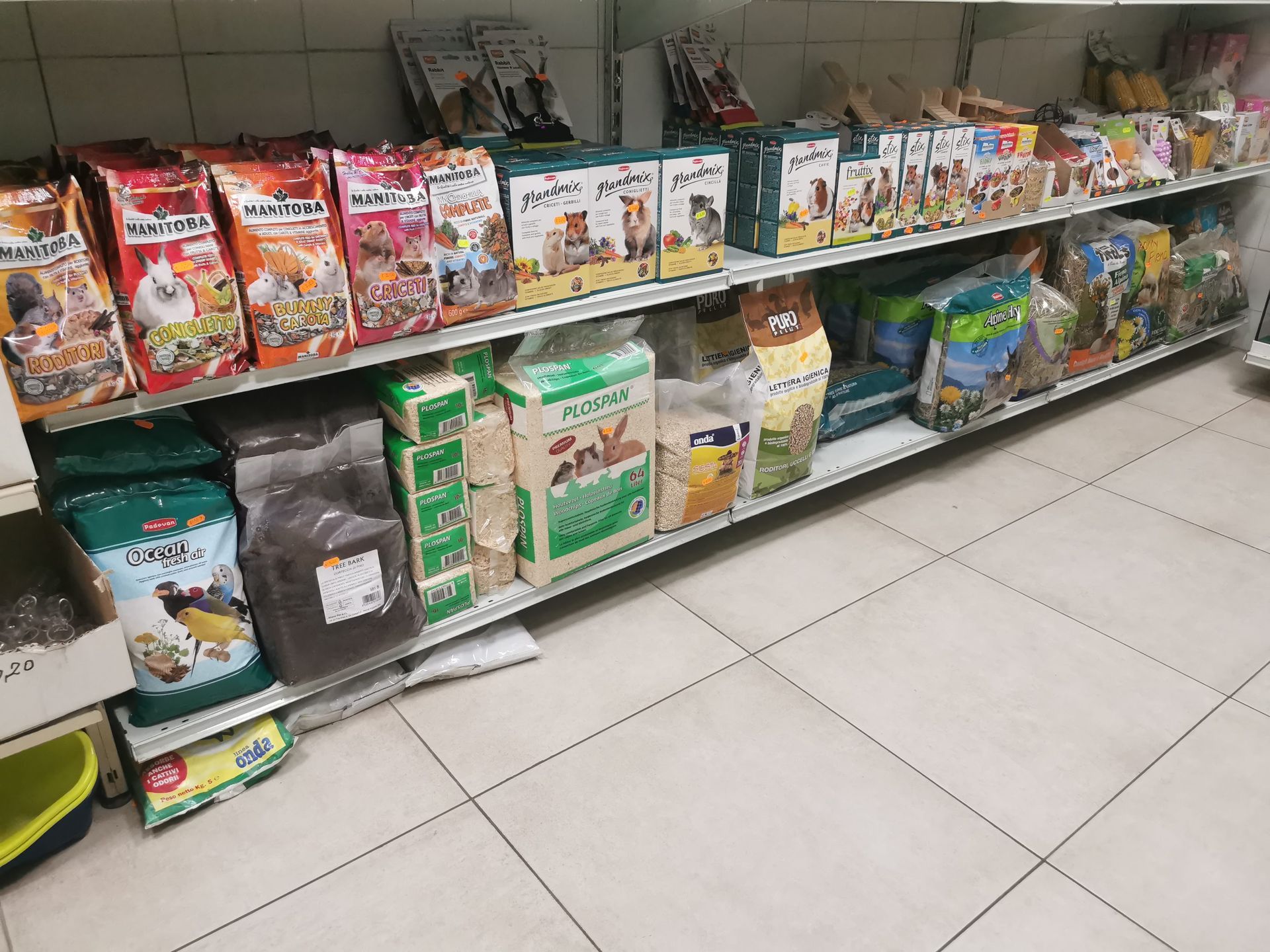 Scaffali di un negozio pieni di sacchi e scatole di cibo e lettiere per animali domestici.