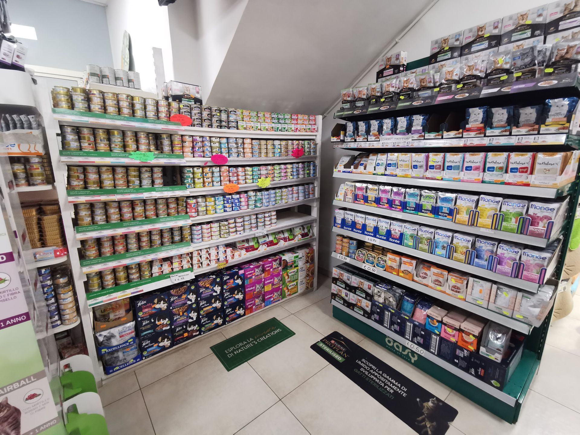 Scaffali di un negozio pieni di vari prodotti alimentari, tra cui cibi in scatola, articoli confezionati in scatole e piccoli contenitori.