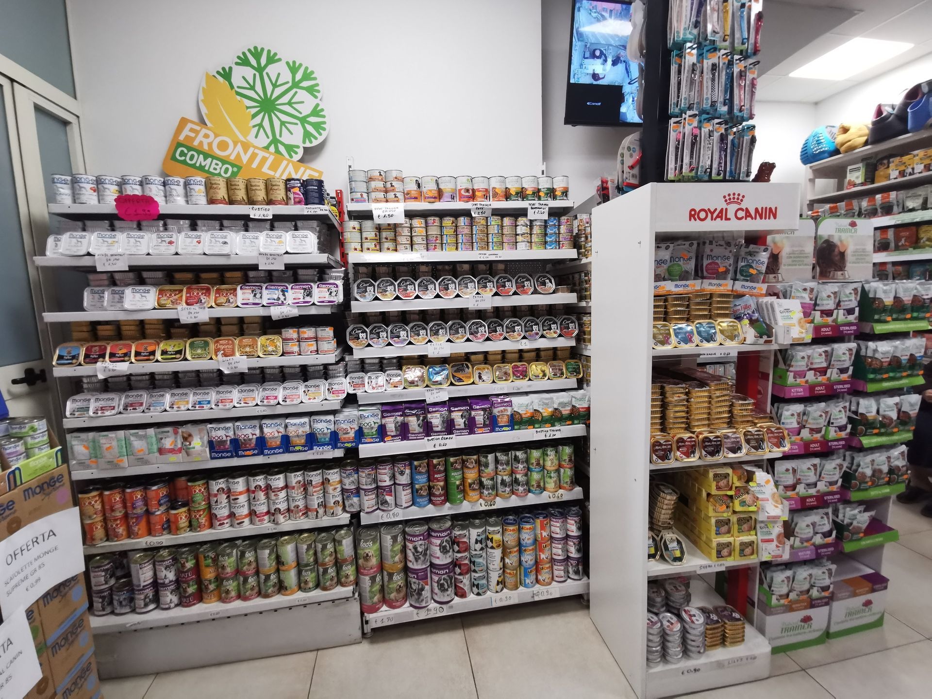 Scaffali di un negozio di articoli per animali pieni di lattine e scatole di cibo per cani e gatti di vario tipo, inclusi prodotti a marchio Royal Canin.