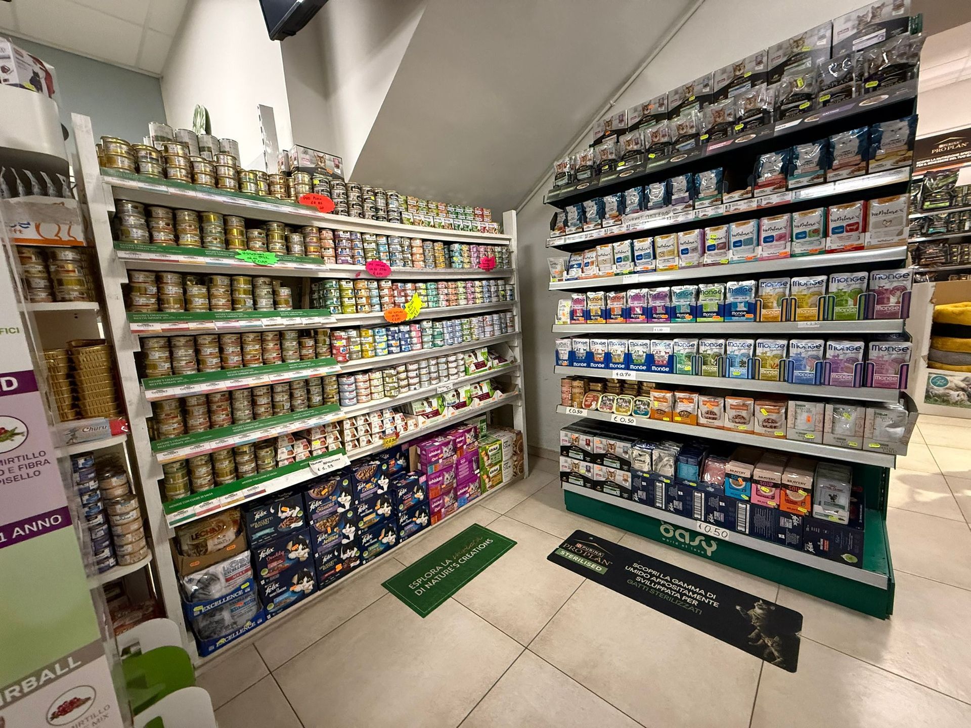 Scaffali di un negozio al dettaglio riforniti con vari prodotti in scatola e alimenti per animali domestici.