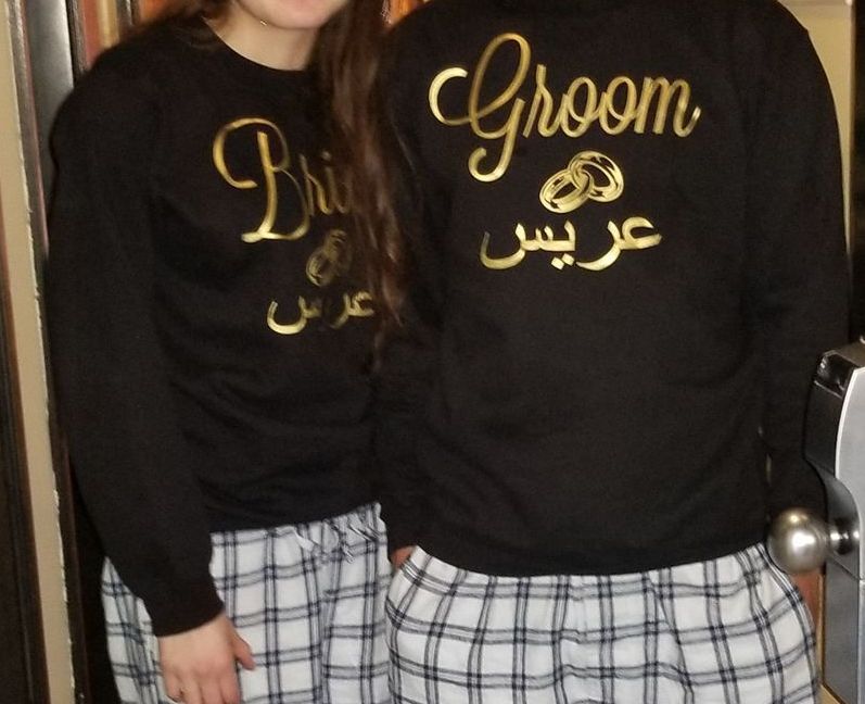 Bride and Groom wearing matching black shirts with gold lettering and plaid pajama pants.