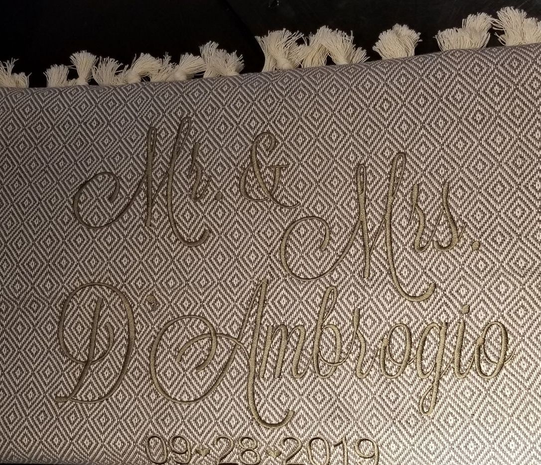 Close-up of a gray, patterned fabric with embroidered text that reads