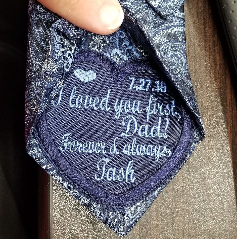 Navy blue tie with a embroidered patch. It reads