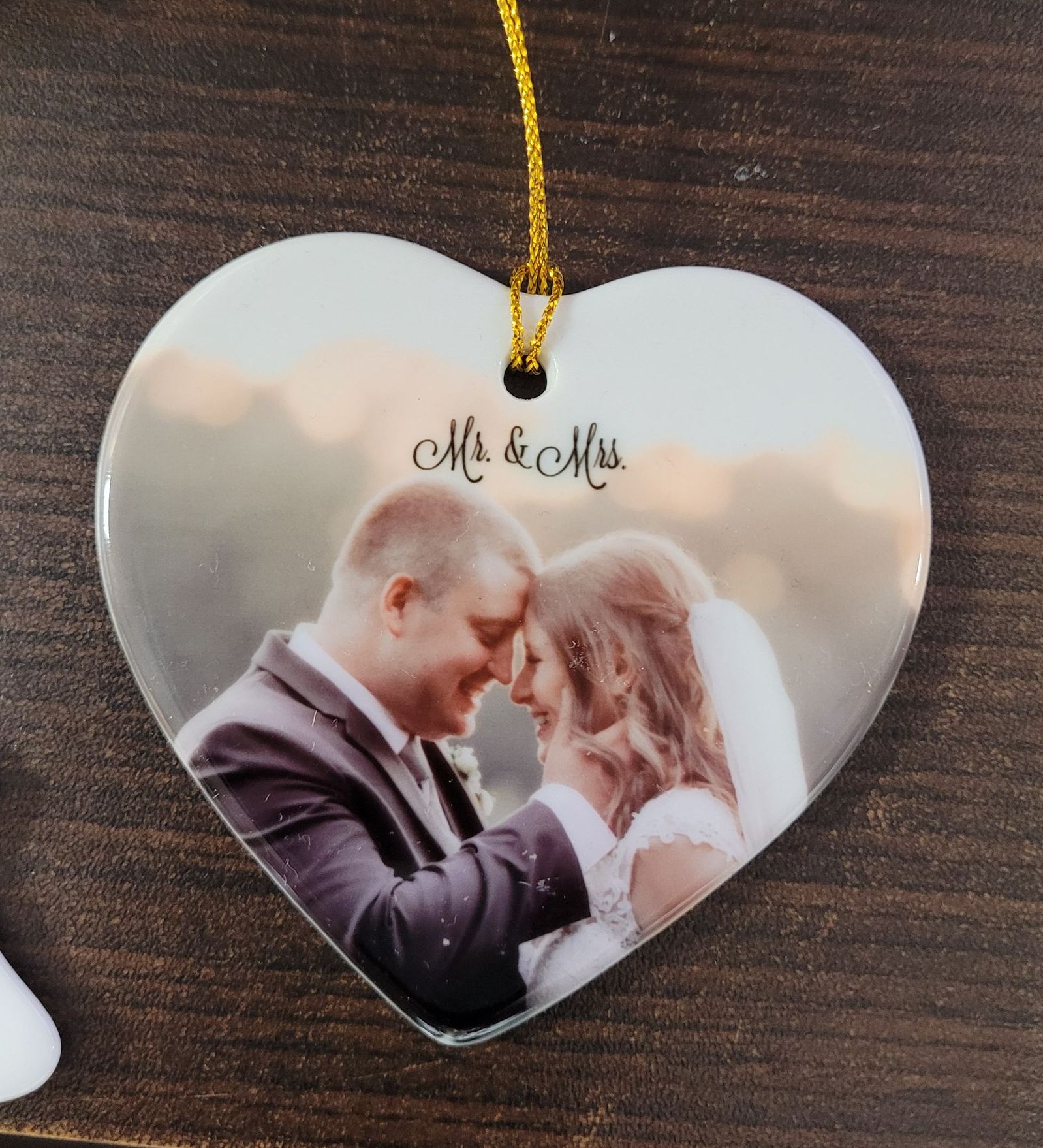 Heart-shaped ornament with a wedding photo of a smiling couple, and the words