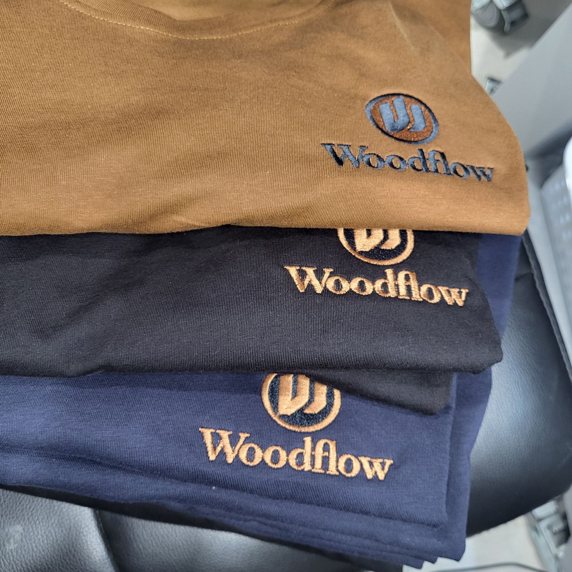 Three folded shirts: brown, black, and navy, each with