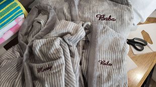 Gray striped robes with embroidered names: Sasha, Milo, and Moody; scissors on a table.