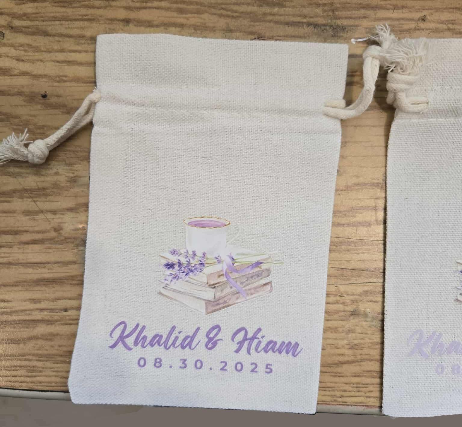 White favor bag with lavender print: stacked books, teacup, couple's names, and wedding date.