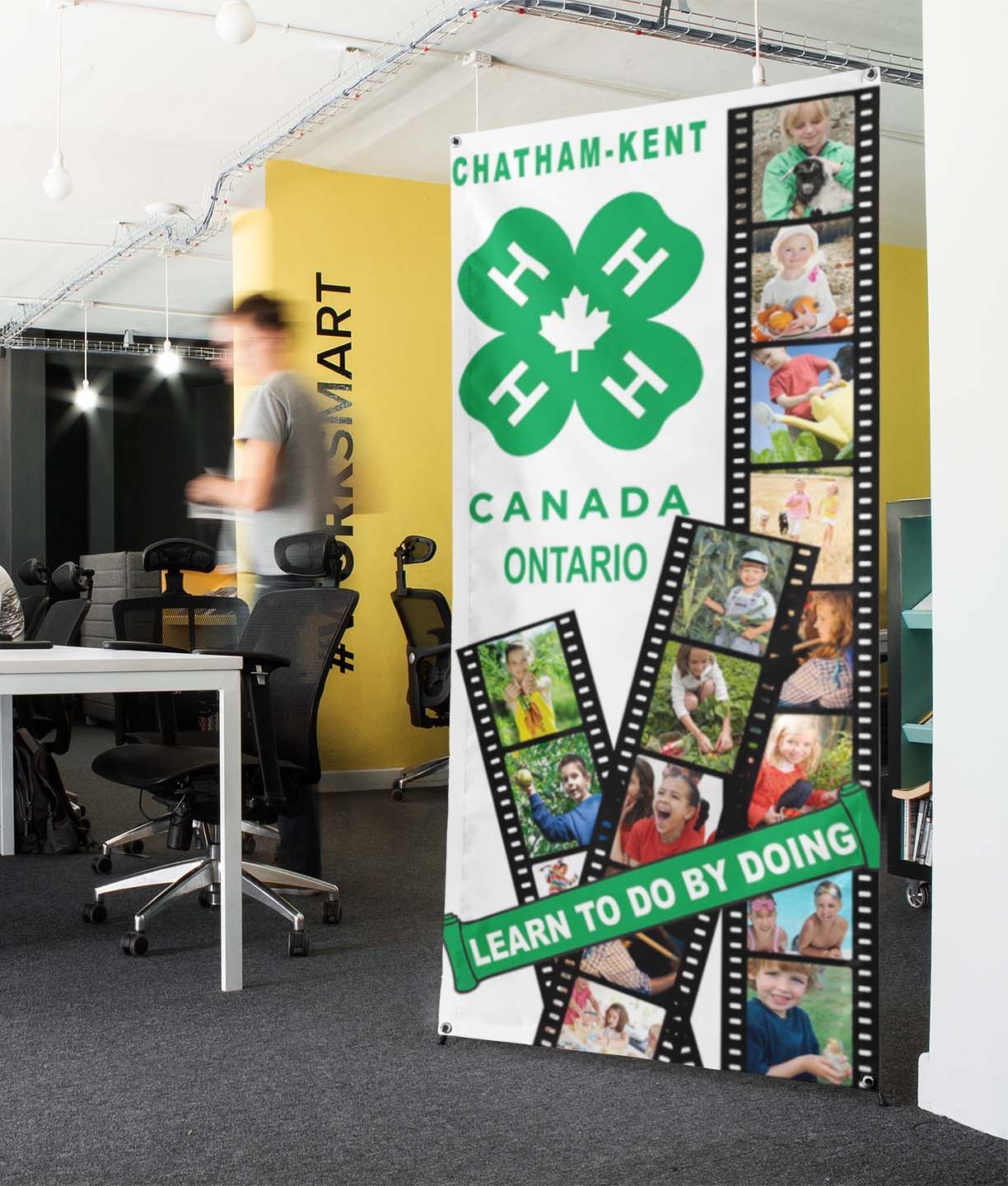 Banner in office: Chatham-Kent 4-H Canada advertisement with photos of children. Person walks by.