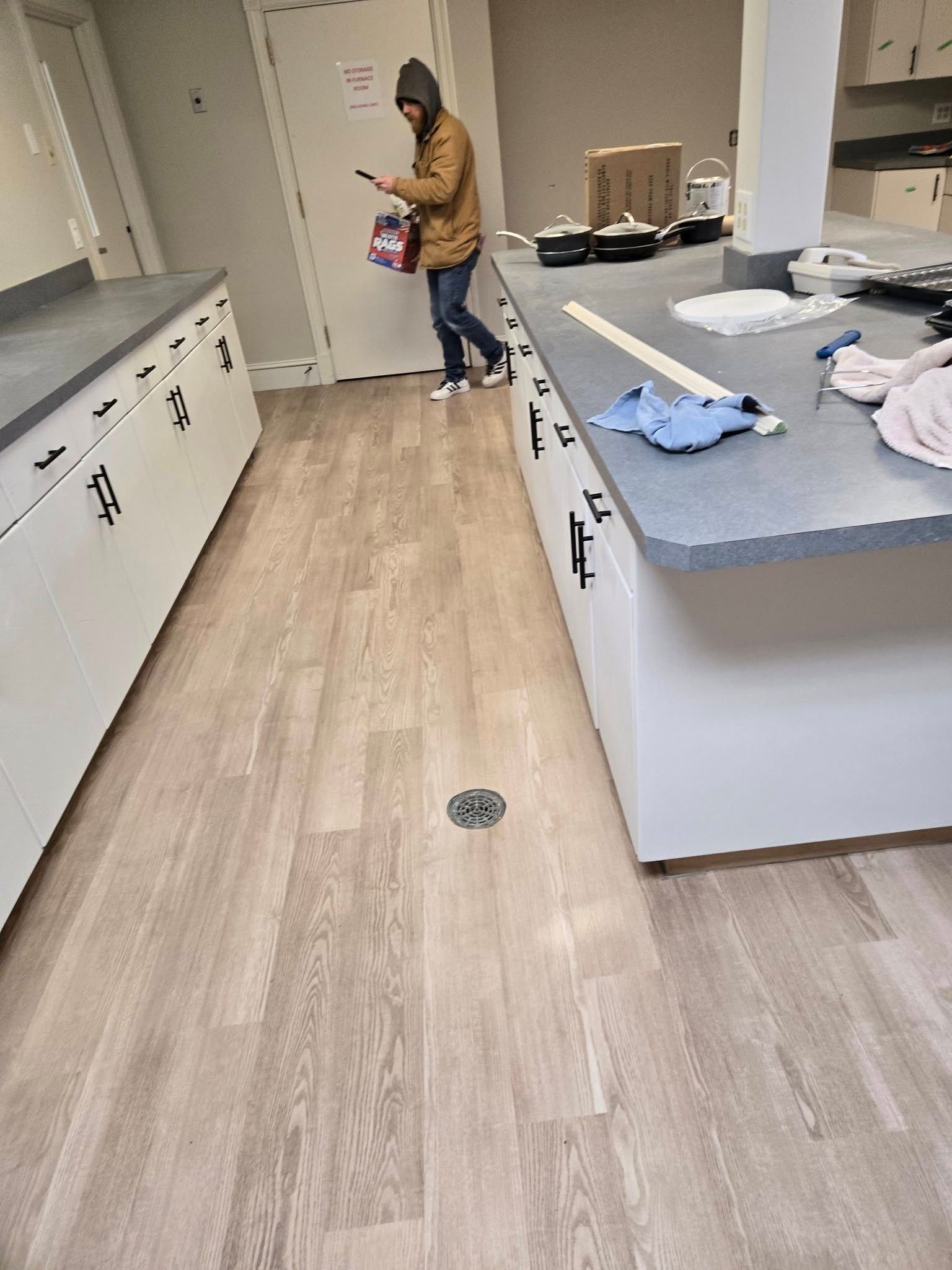 A man is standing in a kitchen looking at his phone.