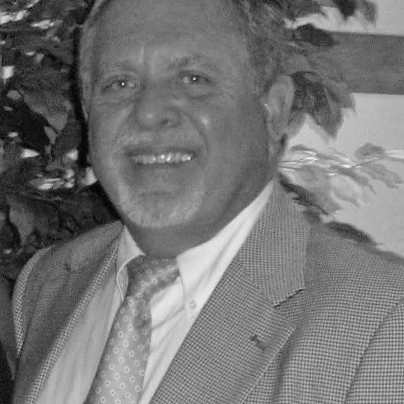 A man in a suit and tie is smiling in a black and white photo.