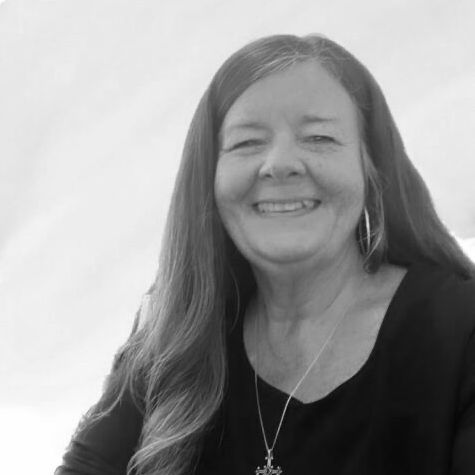 A woman with long hair is smiling in a black and white photo.