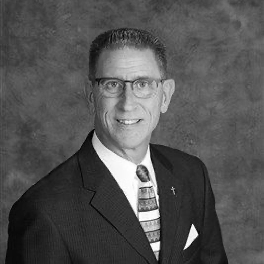 A man in a suit and tie is smiling in a black and white photo.