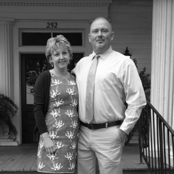 A man and a woman standing in front of a building with the number 252 on it