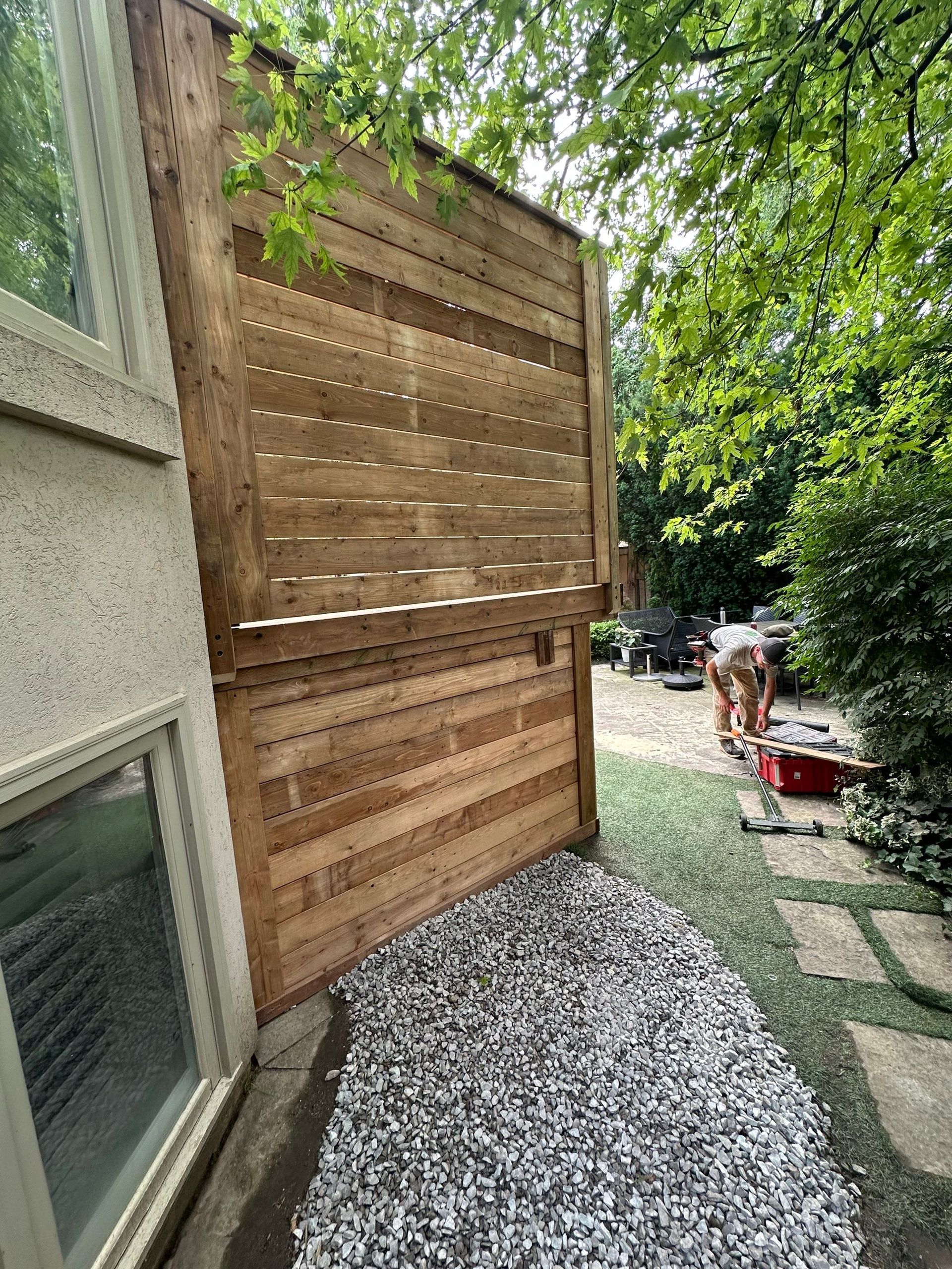 A wooden fence is being built in the backyard of a house.