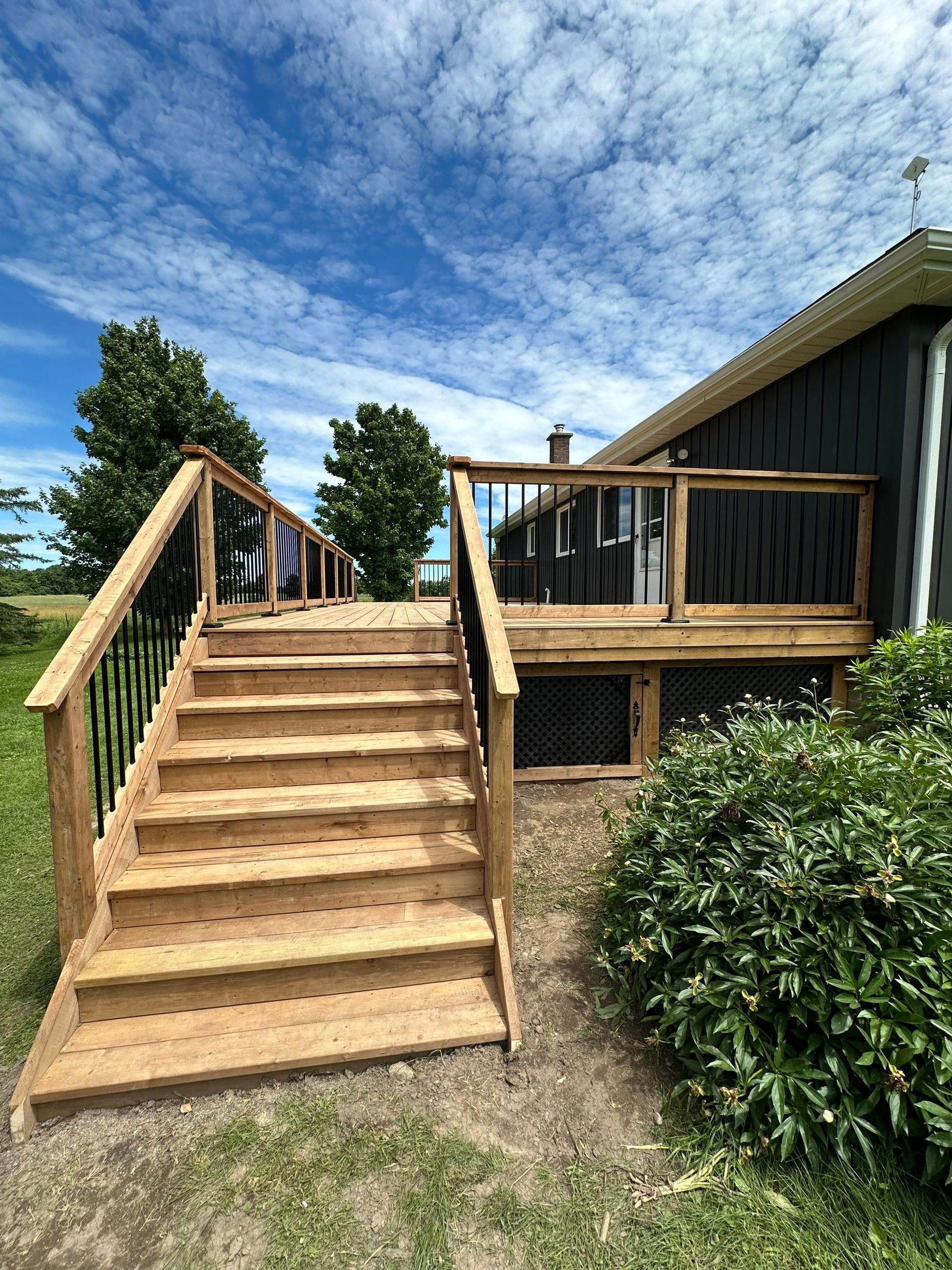 A wooden deck with stairs leading up to it is in front of a house.