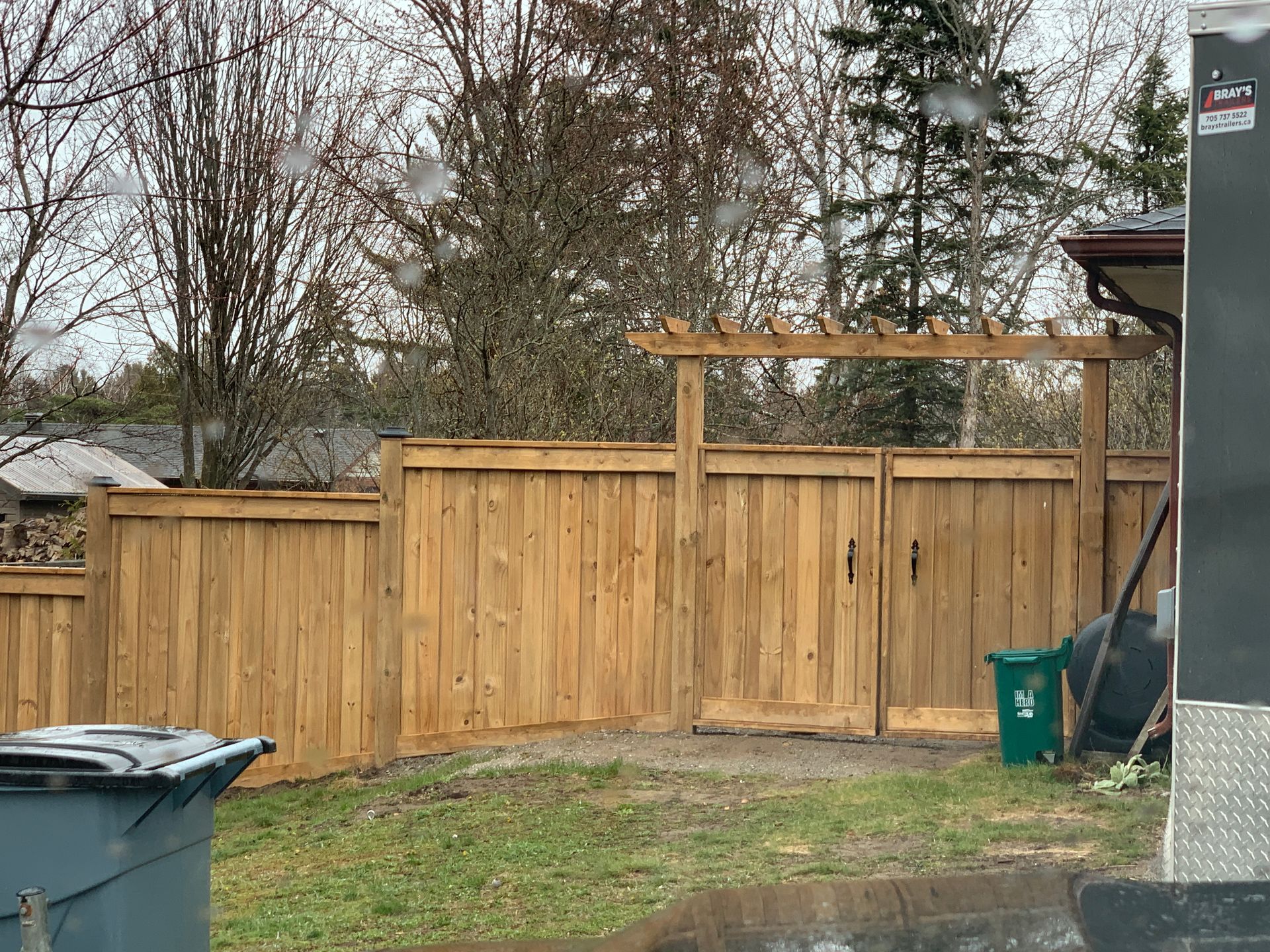 A wooden fence with a gate in the backyard of a house.