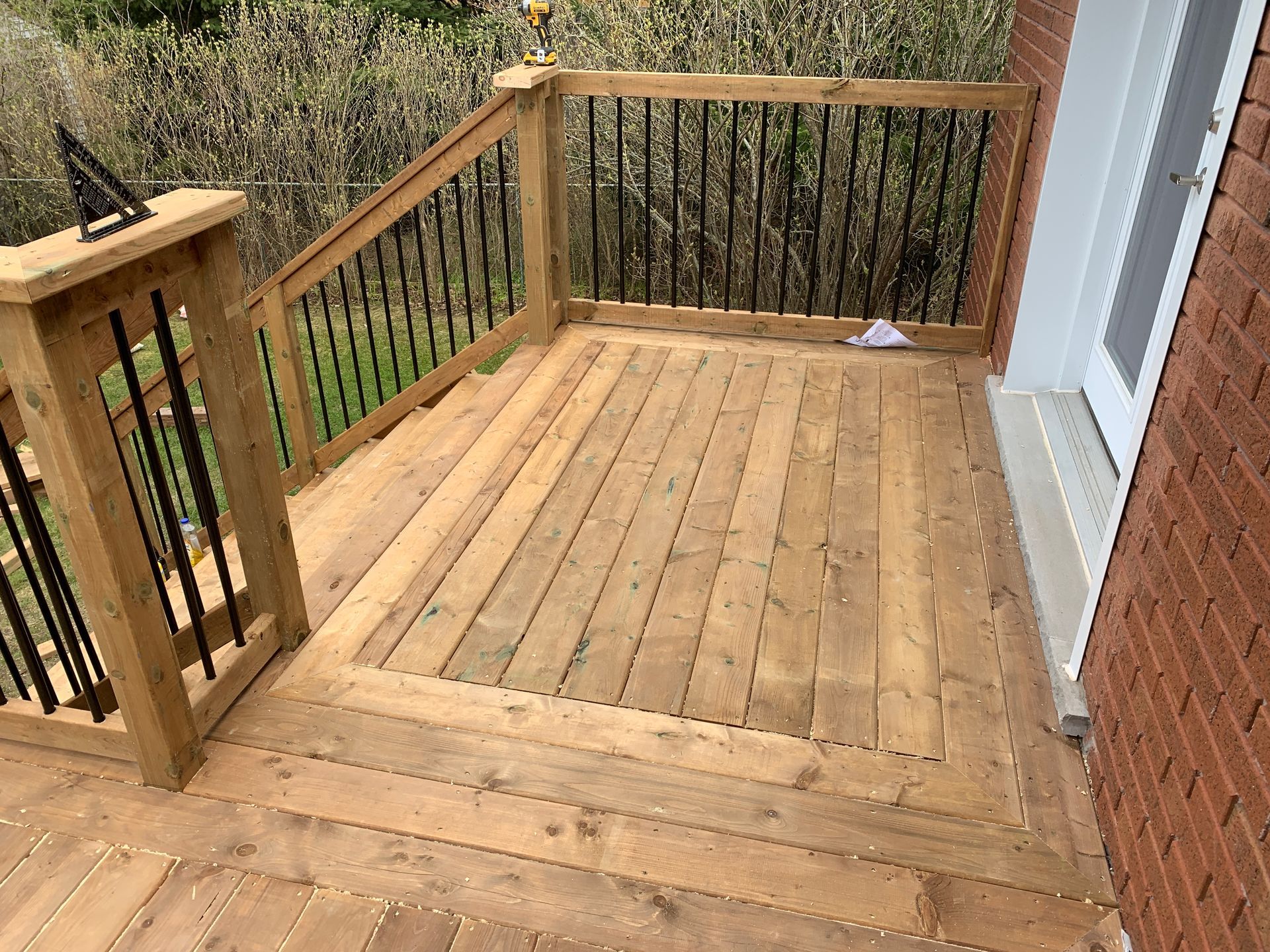 A wooden deck with stairs leading up to it is next to a brick building.
