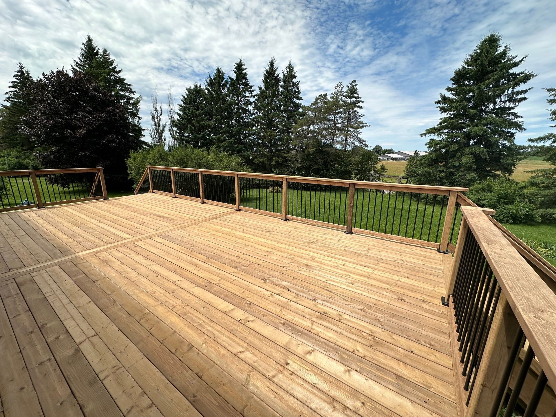 A large wooden deck with trees in the background