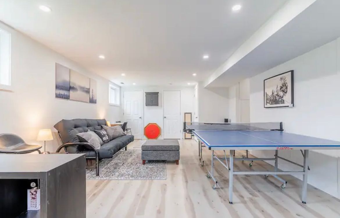 A living room with a ping pong table and a couch.