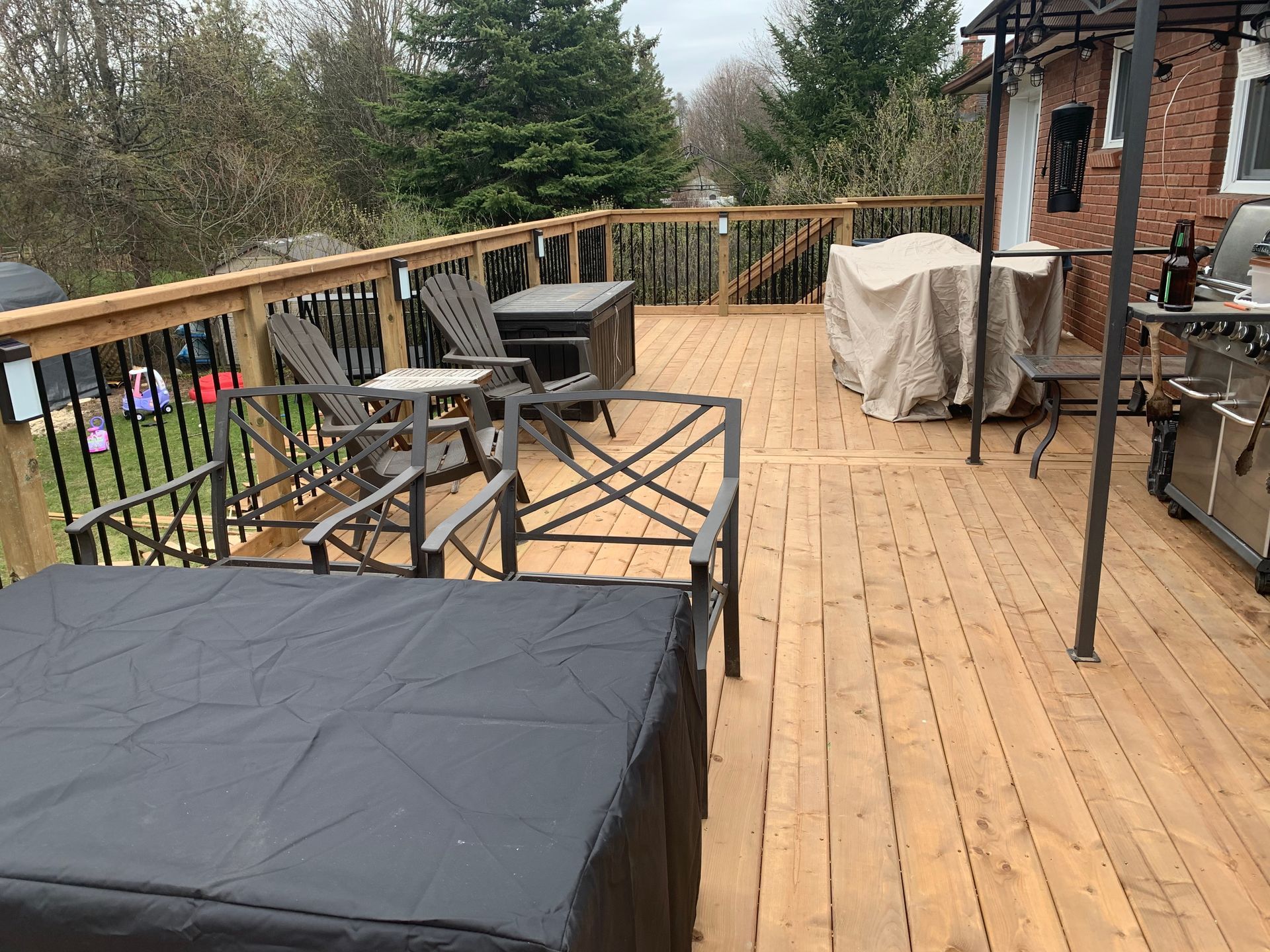 A wooden deck with chairs , a table and a grill.