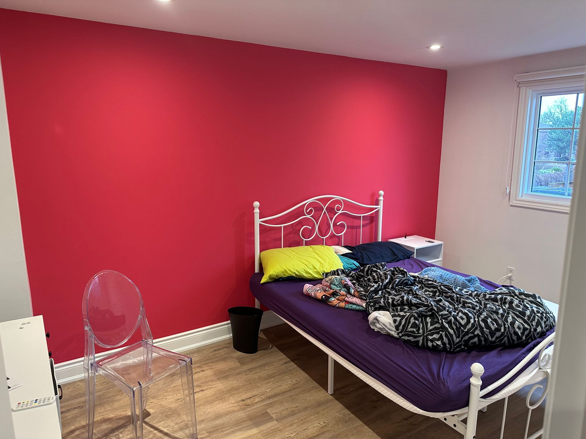 A bedroom with a bed , chair and pink walls.