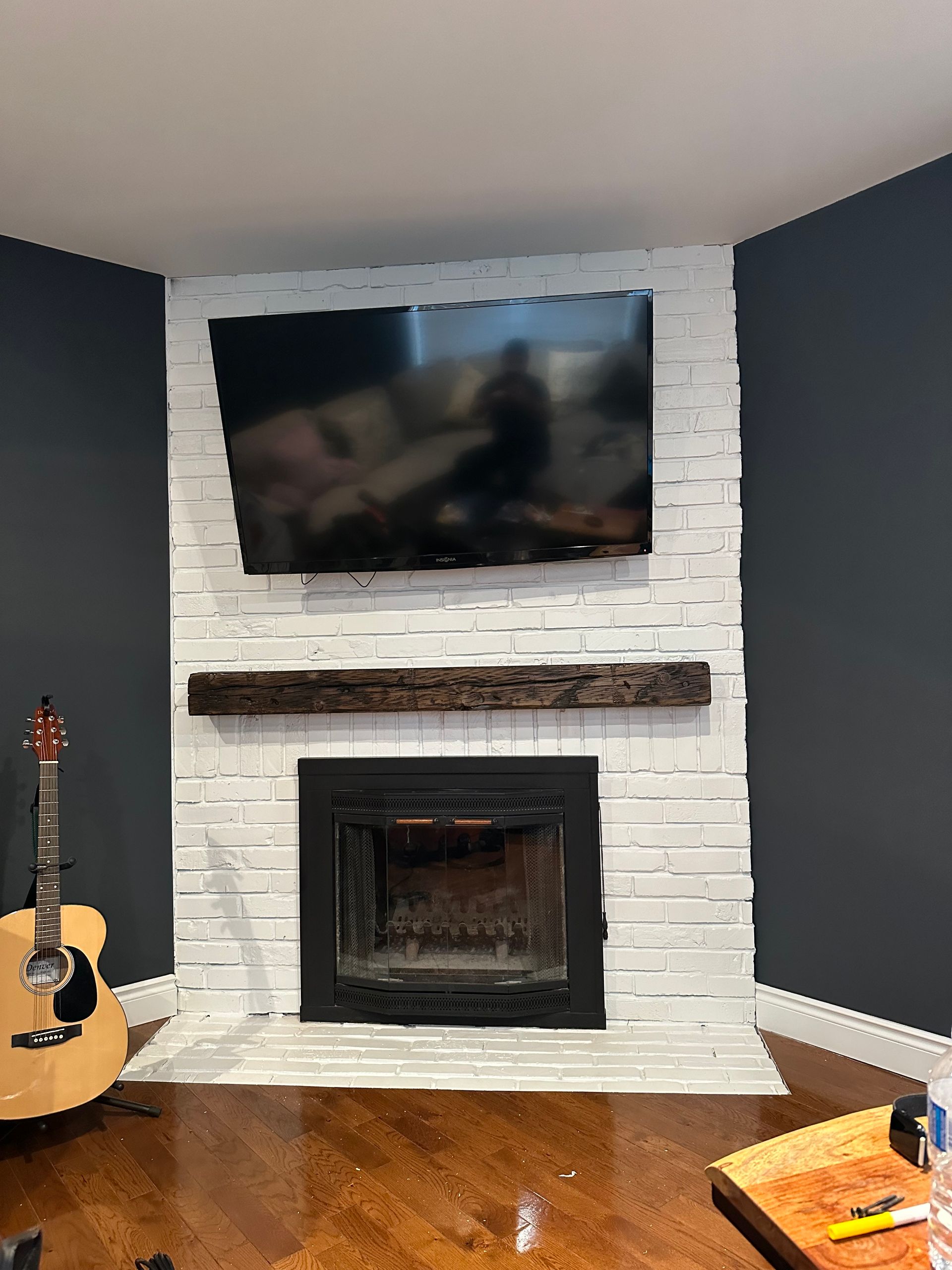 A living room with a fireplace , television , and guitar.