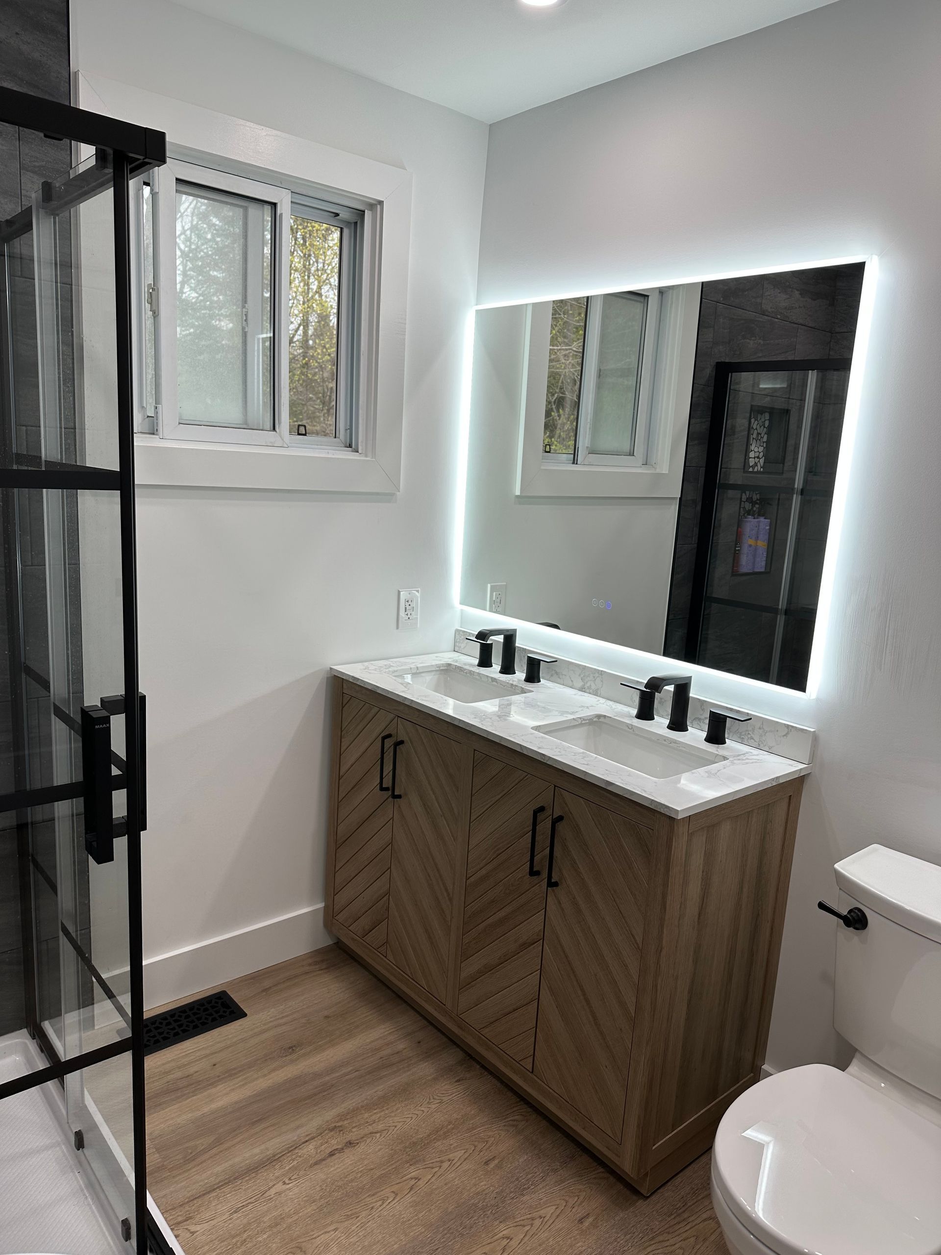 A bathroom with two sinks , a toilet , and a large mirror.