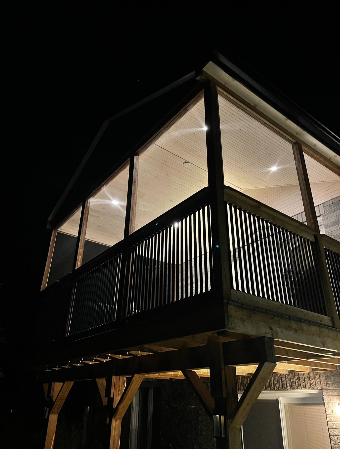 A house with a balcony and a lot of windows at night.