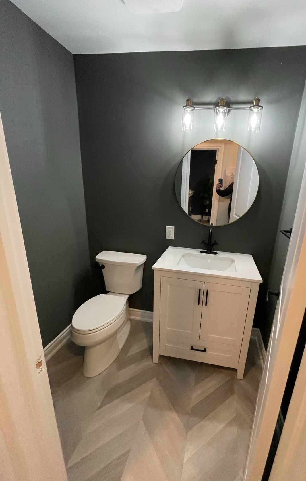 A bathroom with a toilet , sink and mirror.