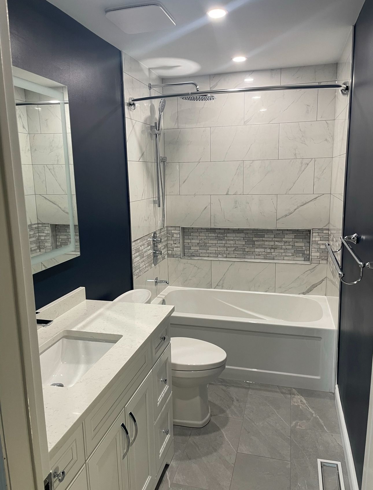 A bathroom with a toilet , sink , bathtub and mirror.