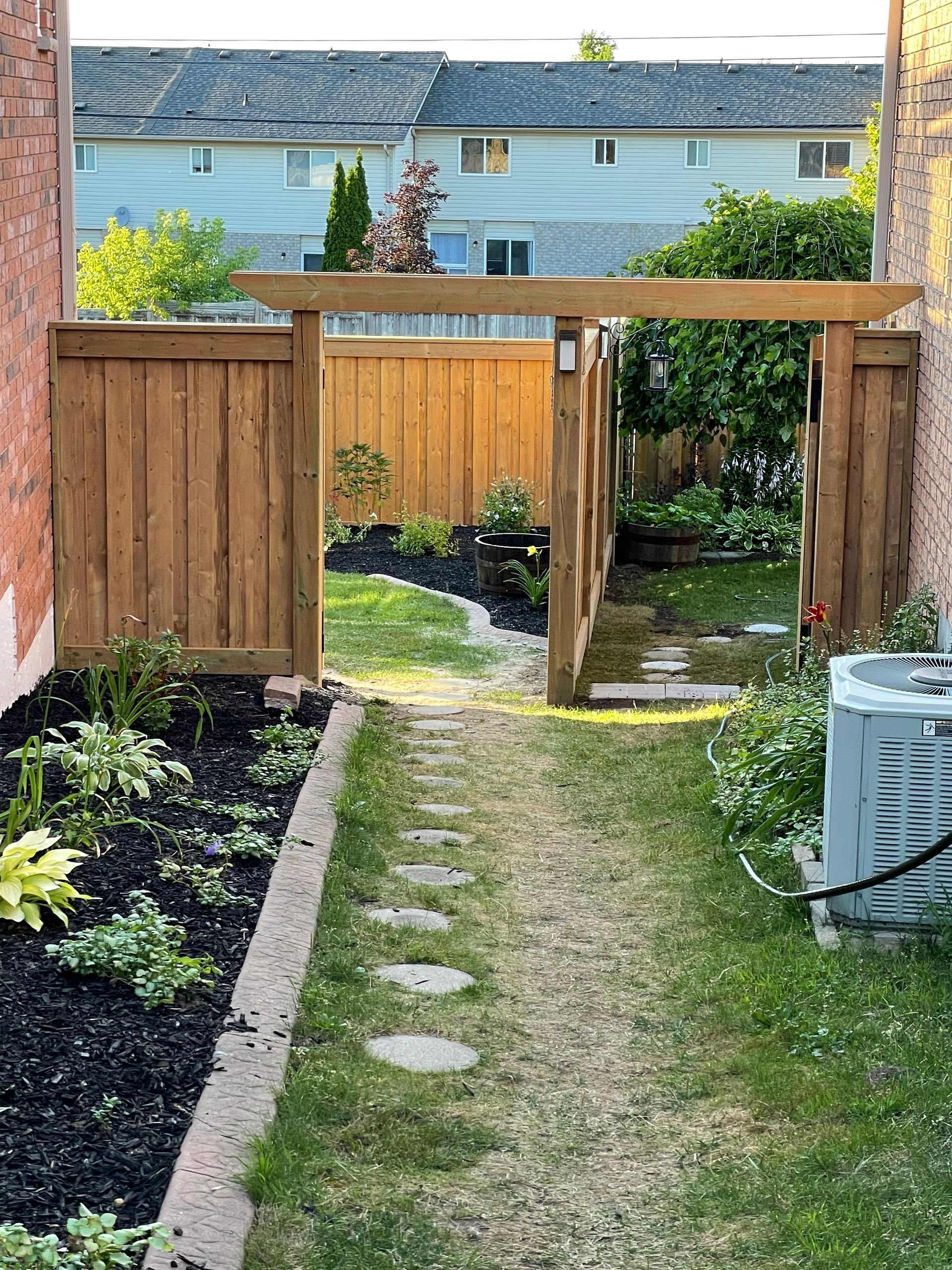 A backyard with a wooden fence and a walkway leading to it.