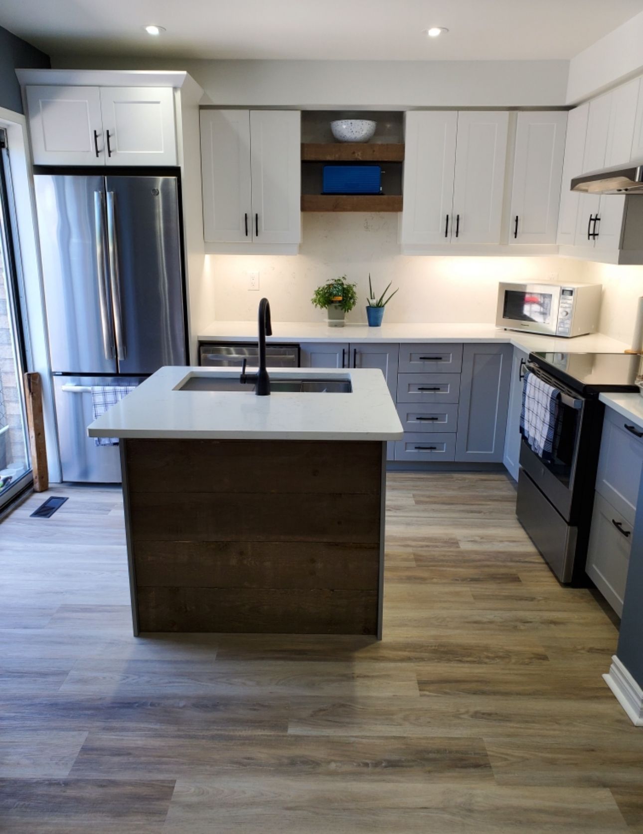 A kitchen with stainless steel appliances and a large island in the middle.