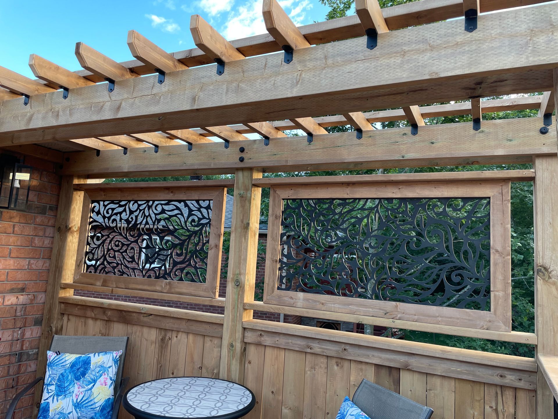 A wooden pergola with a table and chairs underneath it.