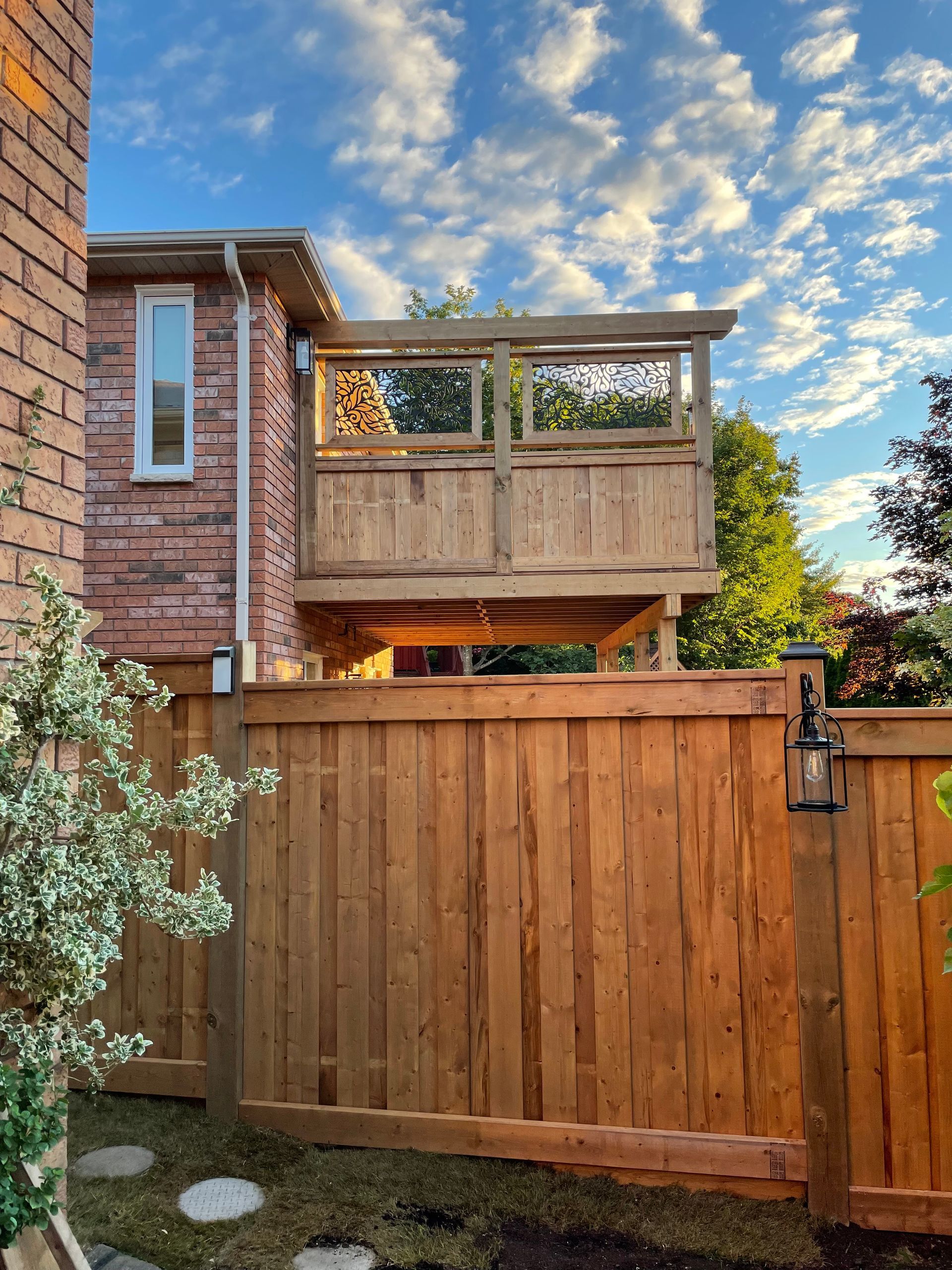 A wooden fence surrounds a house with a deck above it.
