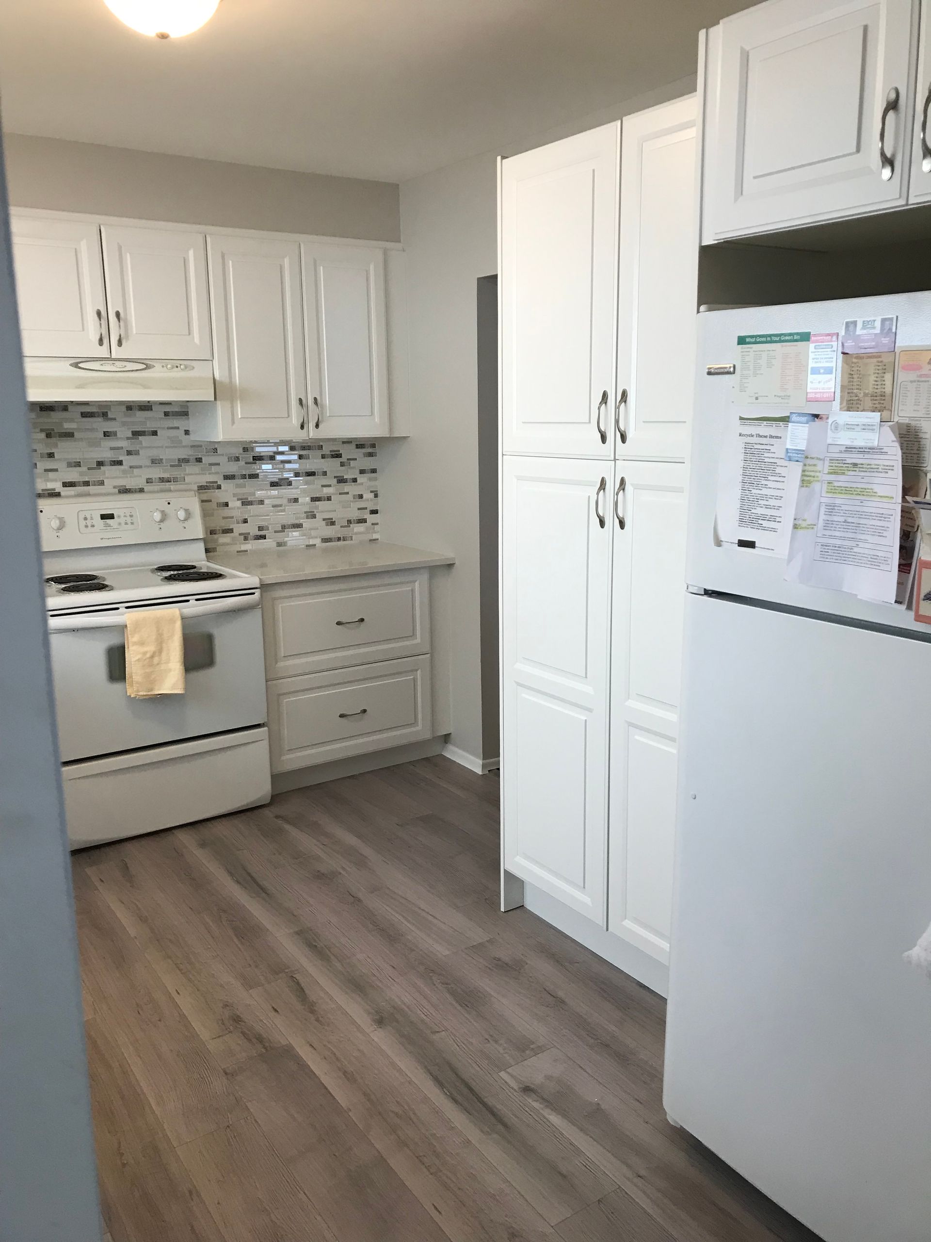 A kitchen with white cabinets , a stove and a refrigerator.