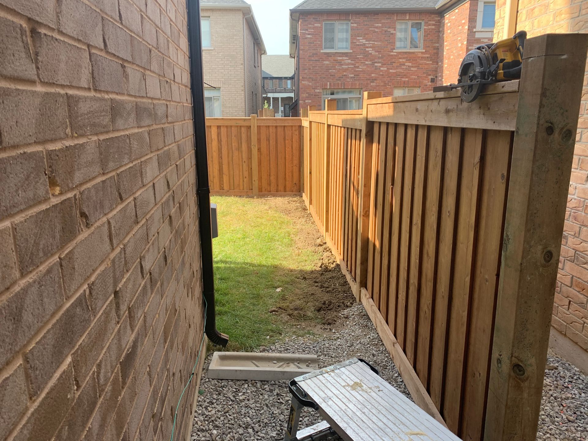 A wooden fence is being built next to a brick wall.