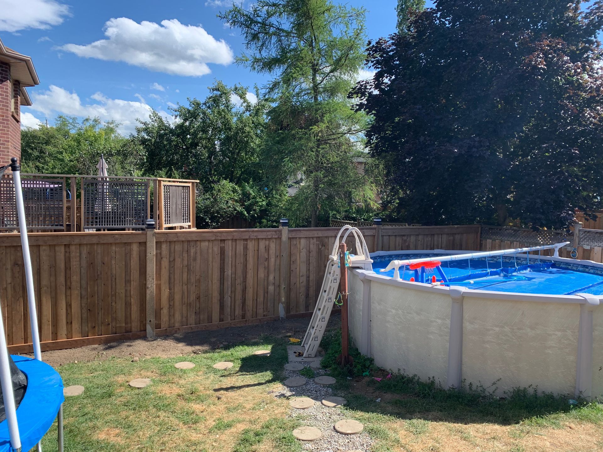 A large swimming pool in a backyard next to a wooden fence.