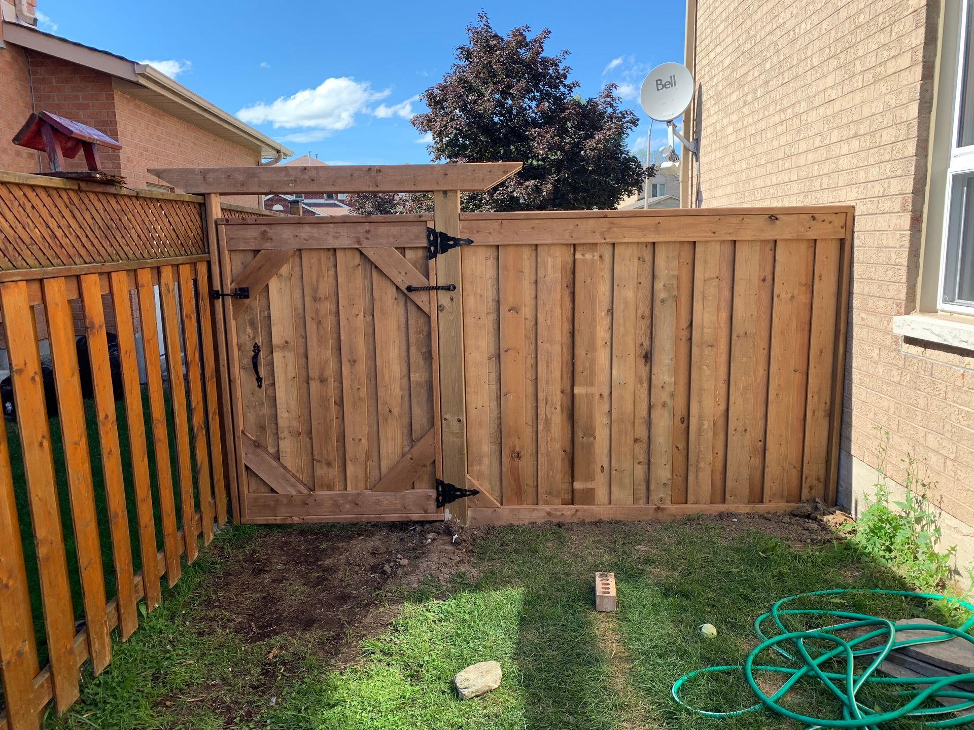 A wooden fence with a gate in the backyard of a house.
