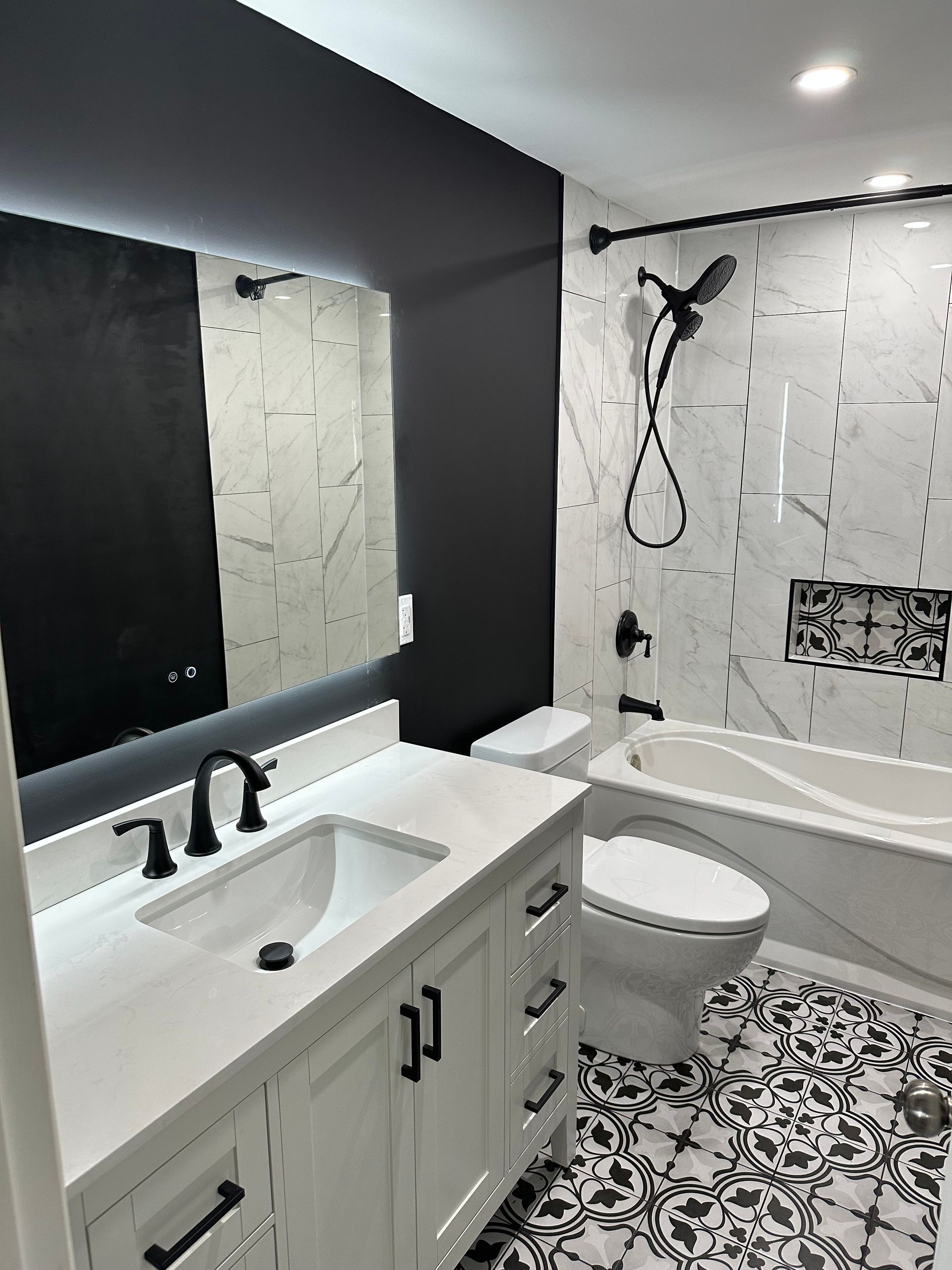 A bathroom with a sink , toilet , bathtub and mirror.